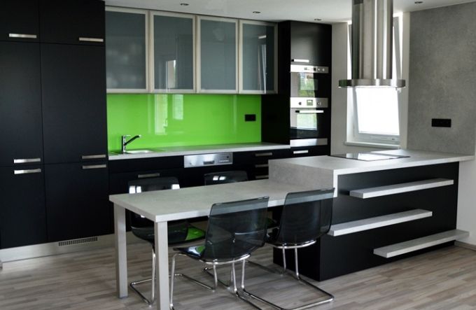 Barevná skleněná deska v kuchyni dokáže rozjasnit celou místnost. V tomto případě byla zvolena sytě zelená v kombinaci s černobílými skříňkami. FOTO: Stylishrooms